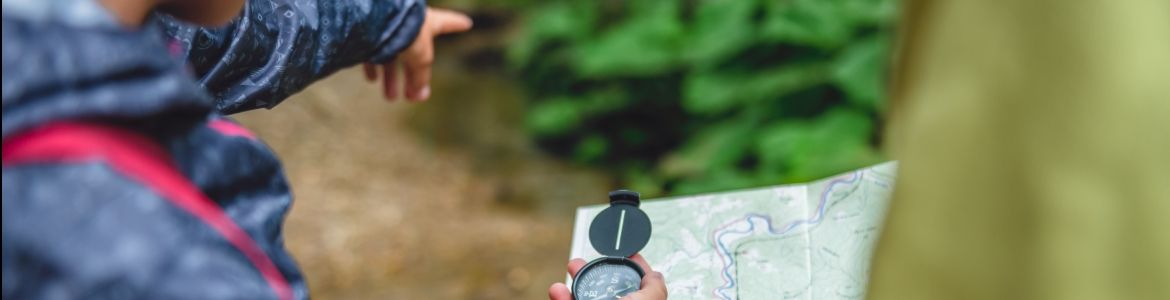man uses compass in the forest